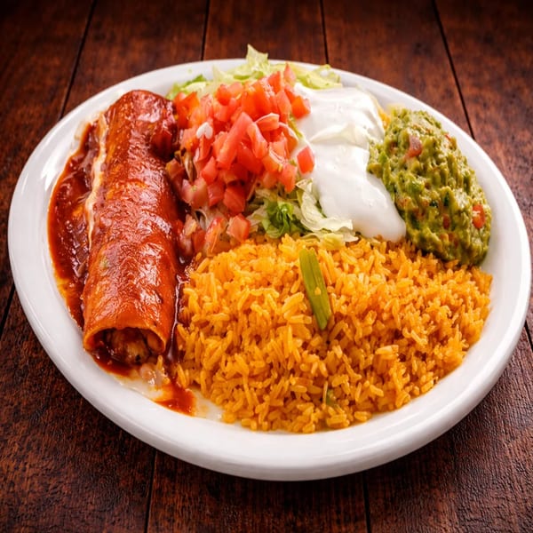 Enchilada plate with red sauce, rice, guacamole, sour cream, lettuce, and diced tomatoes.